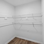 Spacious walk-in closet featuring sleek white wire shelving and elegant wood flooring.