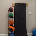 Compact home gym corner featuring a sleek rack with medicine balls and a black exercise mat, ideal for versatile workouts.