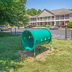 Inviting apartment complex with charming two-story design, ample parking, and a vibrant outdoor play area.