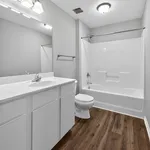 Bright modern bathroom with sleek white fixtures, elegant tub, and chic wood-style flooring.