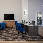 Sophisticated lobby featuring plush blue velvet chairs, a sleek desk, and a modern entertainment area creating a welcoming atmosphere.