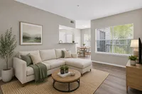 Bright and airy living room with a modern beige sectional, stylish decor, and hardwood floors, adjacent to a cozy dining area with natural light flowing in.