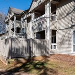 Charming multi-story apartment complex with private balconies and a cozy fenced patio, set in a serene natural environment.