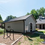 Charming outdoor view of a modern community building with sleek siding, surrounded by lush greenery and open blue skies.