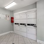 Bright and efficient laundry room with modern, stacked washers and dryers, tiled flooring, and clear usage instructions for convenience.