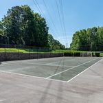 Inviting outdoor tennis court surrounded by lush greenery, perfect for sports enthusiasts seeking leisure and recreation.