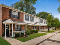 Charming townhome exterior with classic brick facade, lush landscaping, and inviting front porch.