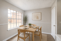 Charming dining area with natural light, featuring a wooden table set for four against a neutral backdrop with elegant decor.