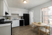Bright and welcoming kitchen with modern black and white appliances, sleek countertops, and a cozy dining area by a large window.
