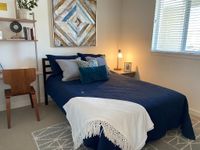 Your Sanctuary Awaits Inviting modern bedroom with a cozy blue bed, stylish art piece, and ambient lighting, perfect for a tranquil retreat.