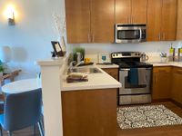 Designed to Inspire Every Meal Modern kitchen with sleek stainless steel appliances, elegant wood cabinetry, and cozy dining area, perfect for entertaining.
