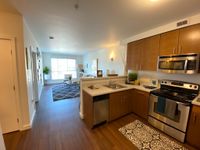 Design That Tastes as Good as It Looks Bright open-concept kitchen-living area with modern stainless steel appliances, cozy decor, and wood flooring.