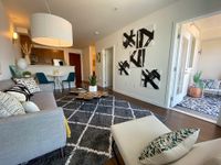 A Place to Call Your Own Contemporary apartment living room with stylish decor, featuring a cozy grey sofa, unique art pieces, and an inviting open kitchen area.