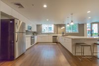 Modern Clubhouse Contemporary kitchen with sleek white cabinetry, stainless steel appliances, and elegant pendant lighting, showcasing a spacious open layout.