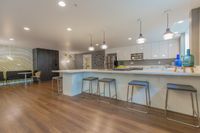 Sip, Chat, Repeat Contemporary open-plan kitchen with sleek white cabinets, modern lighting, and stylish wooden flooring, ideal for entertaining.