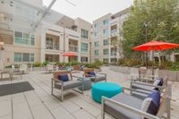 Modern Clubhouse Patio Modern apartment courtyard featuring stylish seating, vibrant red umbrellas, lush greenery, and inviting outdoor space for relaxation and socializing.