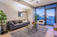 Modern living room with sleek gray couch, stylish decor, and panoramic city views through expansive windows.