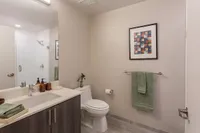 Modern bathroom with sleek vanity, elegant mirror, and vibrant artwork enhancing the neutral decor.