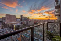 Breathtaking urban skyline view from a modern apartment balcony at sunset, featuring vibrant skies and a bustling cityscape.