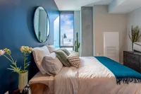 Chic bedroom with a stylish blue accent wall, modern decor, and a bright window view enhancing the airy, tranquil space.