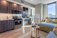 Modern studio apartment featuring an open-concept kitchen and cozy bedroom area, abundant natural light, and stylish decor with city views.