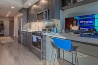 Modern kitchen with sleek cabinetry, stainless steel appliances, and a cozy breakfast bar with a vibrant blue stool. Ideal for entertaining and everyday living.