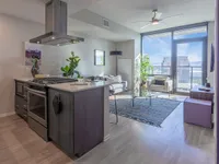 Contemporary urban apartment with a stylish kitchen island, cozy living area, and floor-to-ceiling windows offering stunning city views.