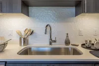 Modern kitchen with sleek quartz countertop, stylish hexagonal backsplash, and elegant stainless steel sink.