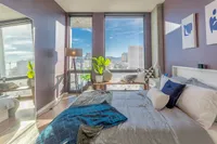 Elegant bedroom with modern furnishings, large windows offering stunning city views, and abundant natural light.