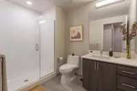 Modern bathroom with sleek vanity, glass-enclosed shower, and elegant decor, showcasing minimalist luxury.