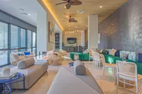 Contemporary lounge area with stylish seating, ceiling fans, and large windows offering natural light and views.