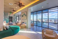 Luxurious modern lounge with artistic decor, featuring plush seating, expansive windows, and scenic outdoor views.