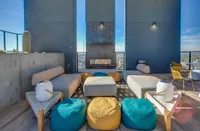 Chic rooftop lounge featuring modern seating, vibrant cushions, and a sleek fireplace with stunning city views.