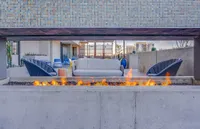 Chic outdoor lounge area with modern seating, vibrant fire pit, and cityscape views.