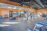 Bright and spacious gym featuring modern fitness equipment, sleek flooring, and ample natural light.