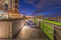 Elegant urban balcony with modern seating, offering stunning cityscape views at dusk.