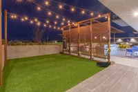Luxurious rooftop patio showcasing a stylish outdoor gym area with string lights, vibrant seating, and captivating night views.