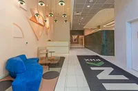 Modern lobby design showcasing a vibrant blue sofa, artistic wall décor, and elegant lighting, perfect for welcoming guests with style.