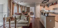 Elegant open-concept living room and kitchen with modern decor, featuring cozy seating, stylish dining area, and sleek hardwood floors.
