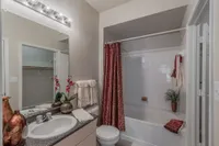 Elegant bathroom with stylish granite countertop, chic red shower curtain, and inviting decor featuring fresh orchids and plush towels.