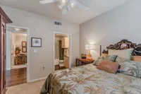 Cozy bedroom with elegant bedding and warm lighting, adjoining a modern en-suite bathroom and charming hallway.
