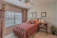 Inviting bedroom with elegant decor, featuring a cozy bed with a vibrant patterned duvet, large window for natural light, and stylish artwork.