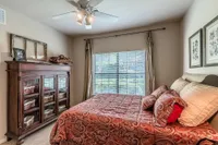 Cozy bedroom featuring elegant wooden furniture, a large sunlit window, and a vibrant paisley-patterned bedspread.