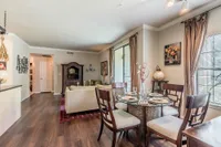 Elegant living and dining area with abundant natural light, featuring stylish furniture and a cozy dining setup perfect for entertaining.