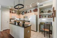 Charming kitchen space with modern lighting, a decorative island, and built-in shelves offering a cozy ambiance.