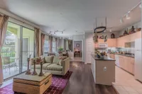 Inviting open-concept living room and kitchen with bright natural light, elegant decor, and a cozy balcony view.