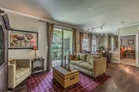 Inviting open-concept living room and kitchen with bright natural light, elegant decor, and a cozy balcony view.