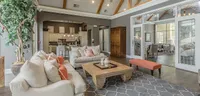 Inviting open-concept living room with plush sofas, vibrant cushions, and elegant decor, connected to a modern kitchen, perfect for stylish entertaining.