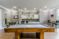 Chic game room with a billiard table, modern lighting, and a cozy seating area, perfect for entertaining in style.