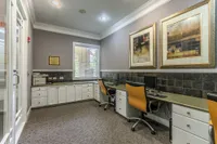 Elegant office space in upscale apartment complex featuring modern workstations, chic artwork, and abundant natural light.